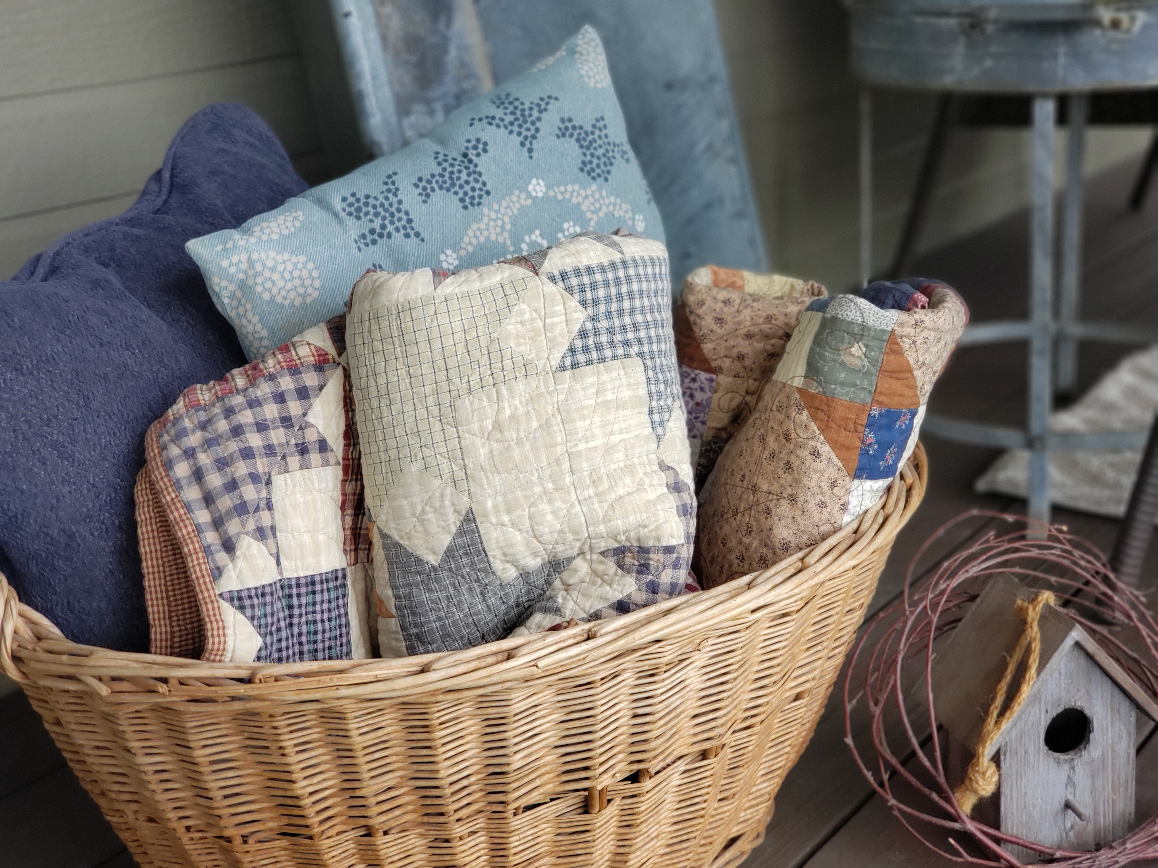 basket of quilts and pillows on a fall porch